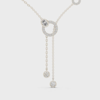 Lariat diamond necklace featuring a large circular motif with two drop pendants on polished metal