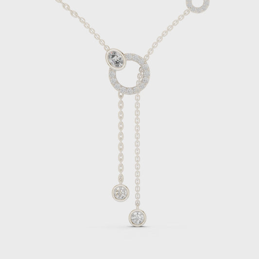 Lariat diamond necklace featuring a large circular motif with two drop pendants on polished metal