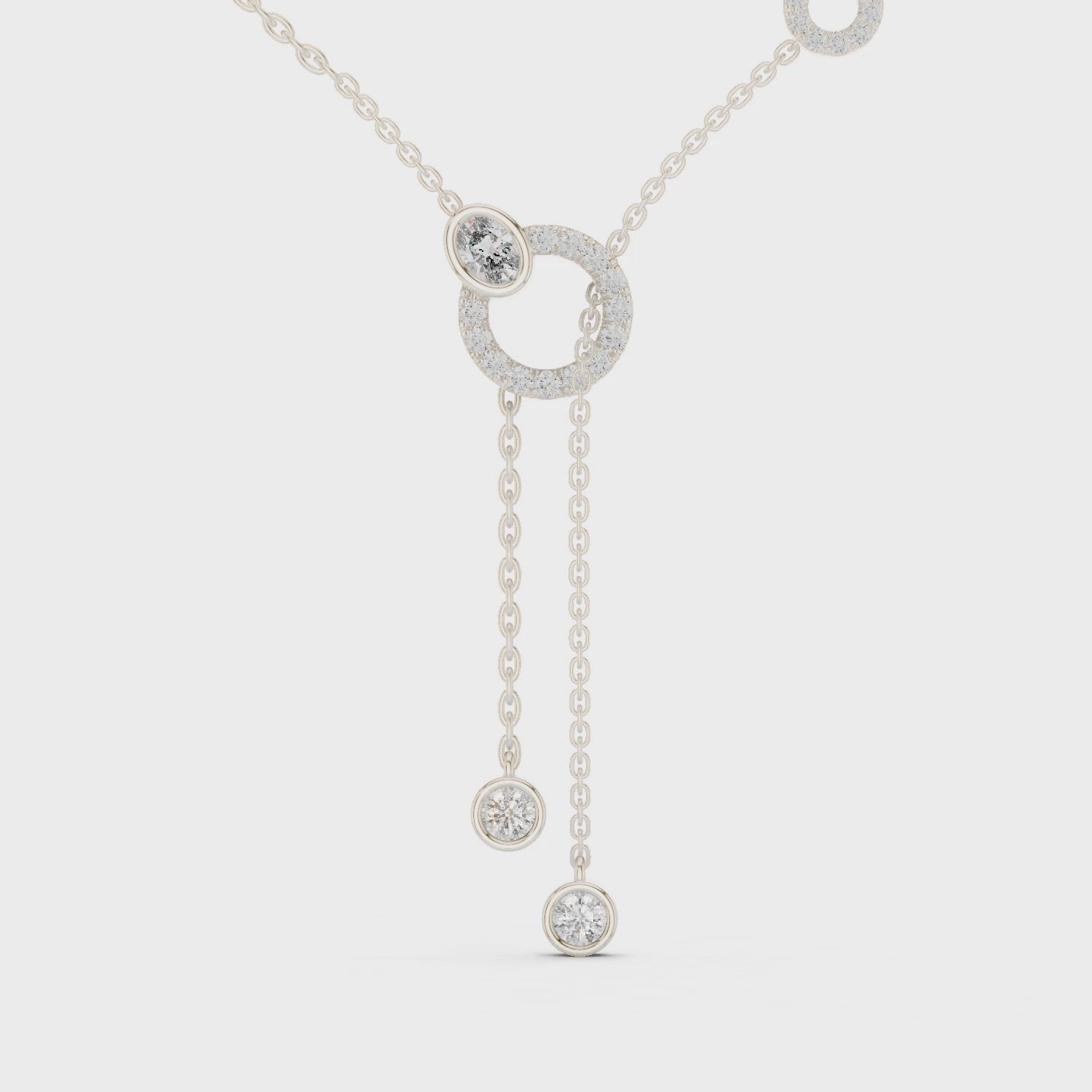 Lariat diamond necklace featuring a large circular motif with two drop pendants on polished metal